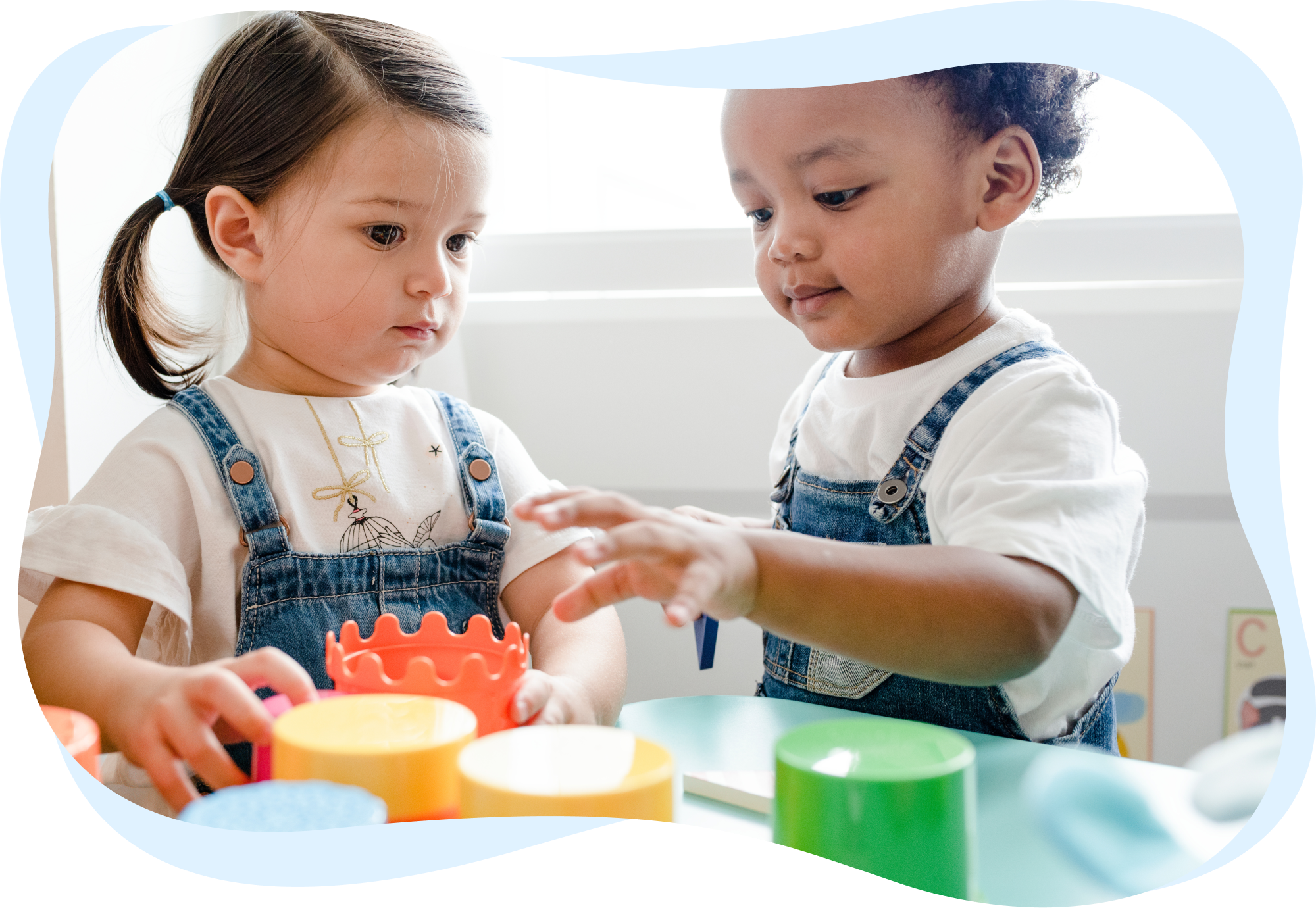 wo toddlers concentrating on playing with colorful stacking toys.